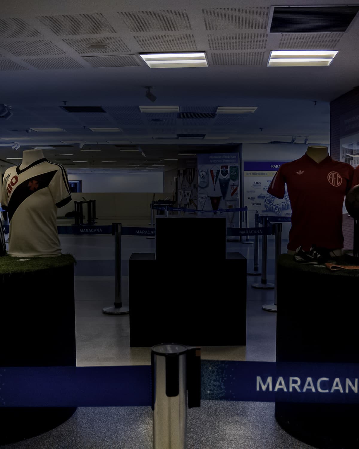 El vestíbulo de entrada del Tour del Maracanã, con los mostradores bajo el rótulo MARACANÃ, camisetas históricas expuestas sobre pedestales y los torniquetes al fondo.