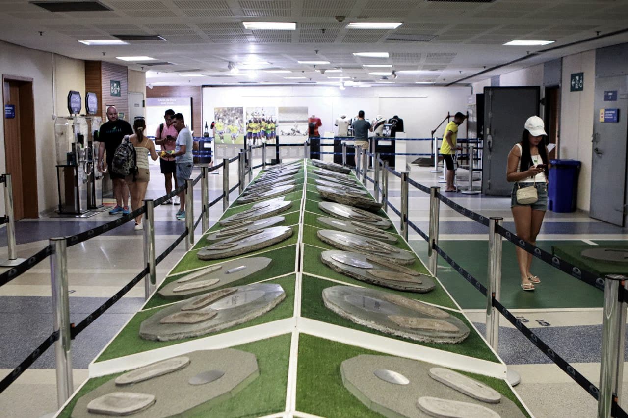 Calçada da Fama do Maracanã: as marcas dos pés de jogadores em placas de cimento, com visitantes ao fundo.