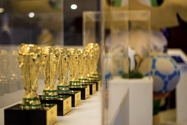 Fileira de réplicas douradas de troféus na vitrine do acervo histórico.