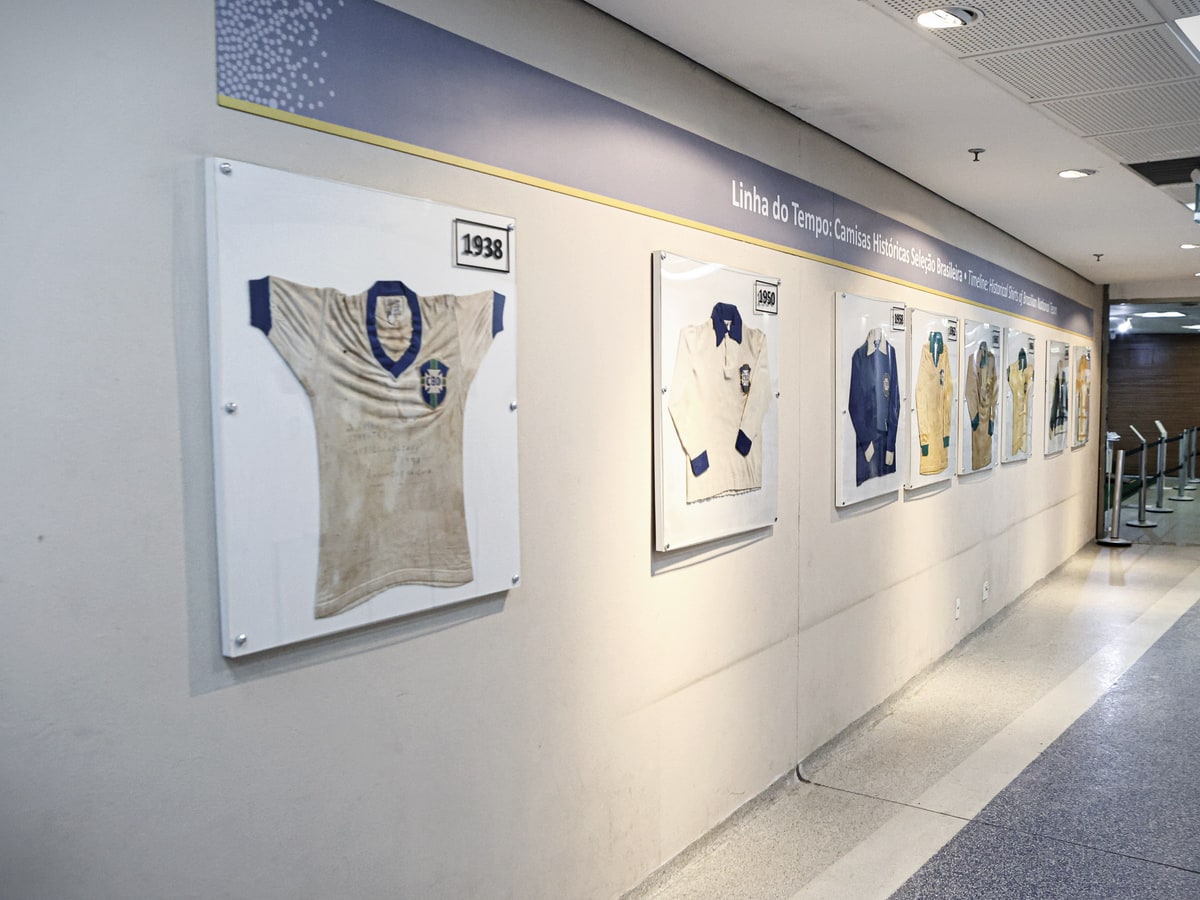 The timeline of Brazil shirts in the Maracanã museum: framed shirts on the wall, the 1938 one in the foreground, and the level-floored corridor running to the far end.