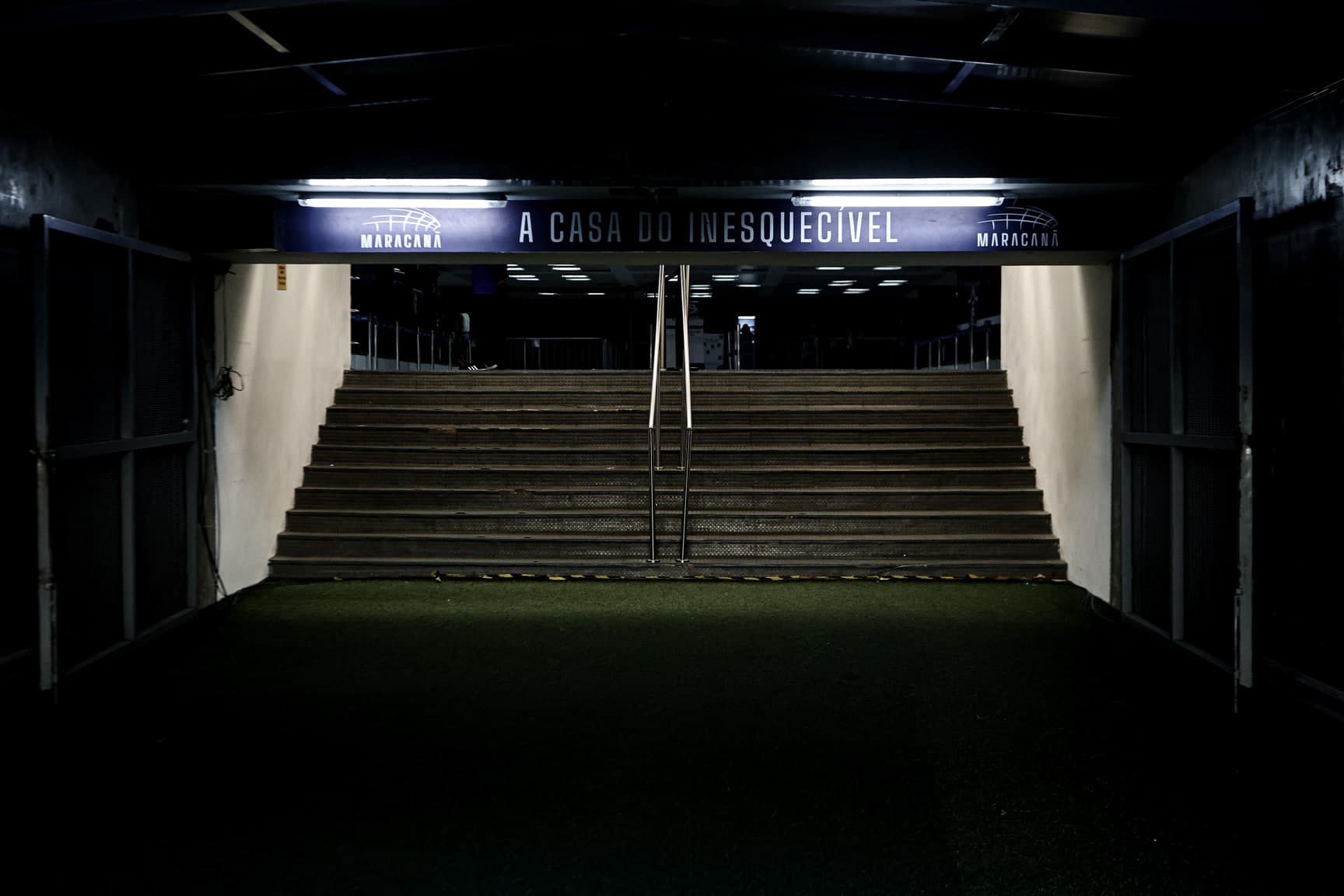O túnel de acesso ao gramado, com a escada subindo para o campo sob a faixa "A casa do inesquecível".