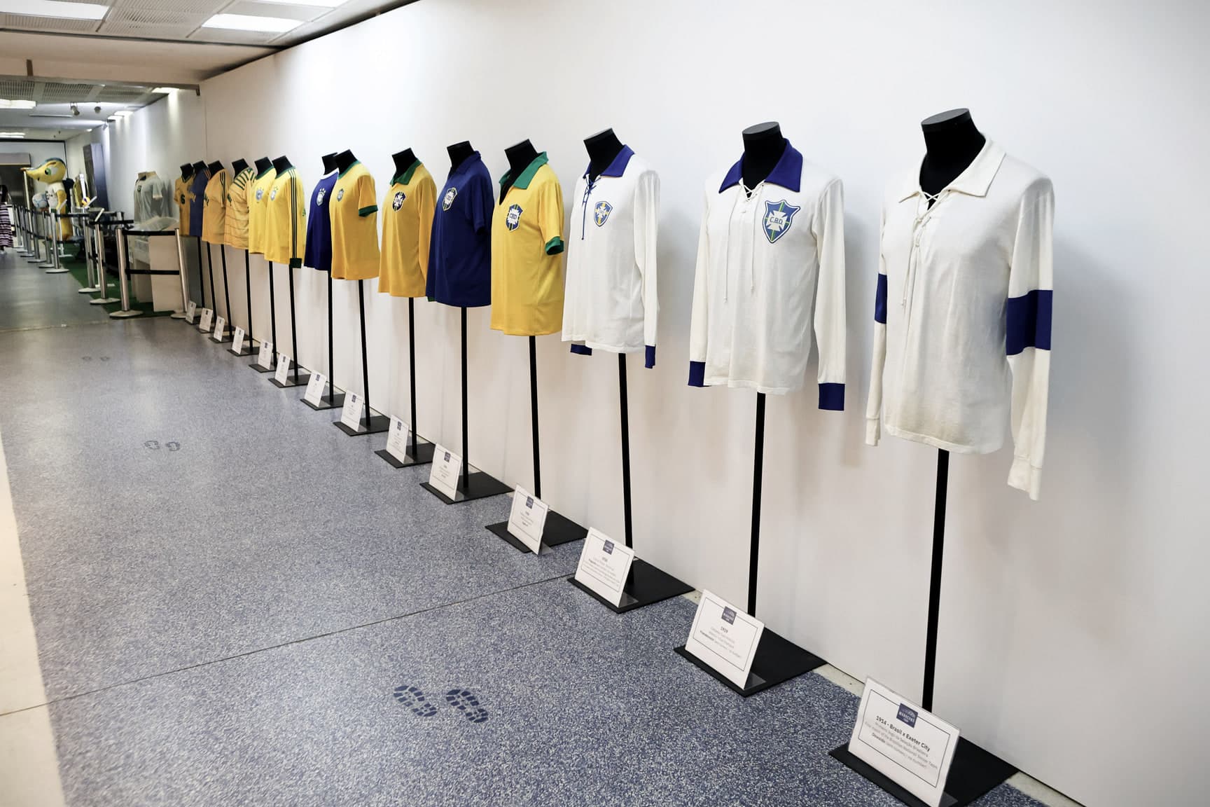 Corredor do acervo com manequins vestindo camisas históricas da seleção brasileira.