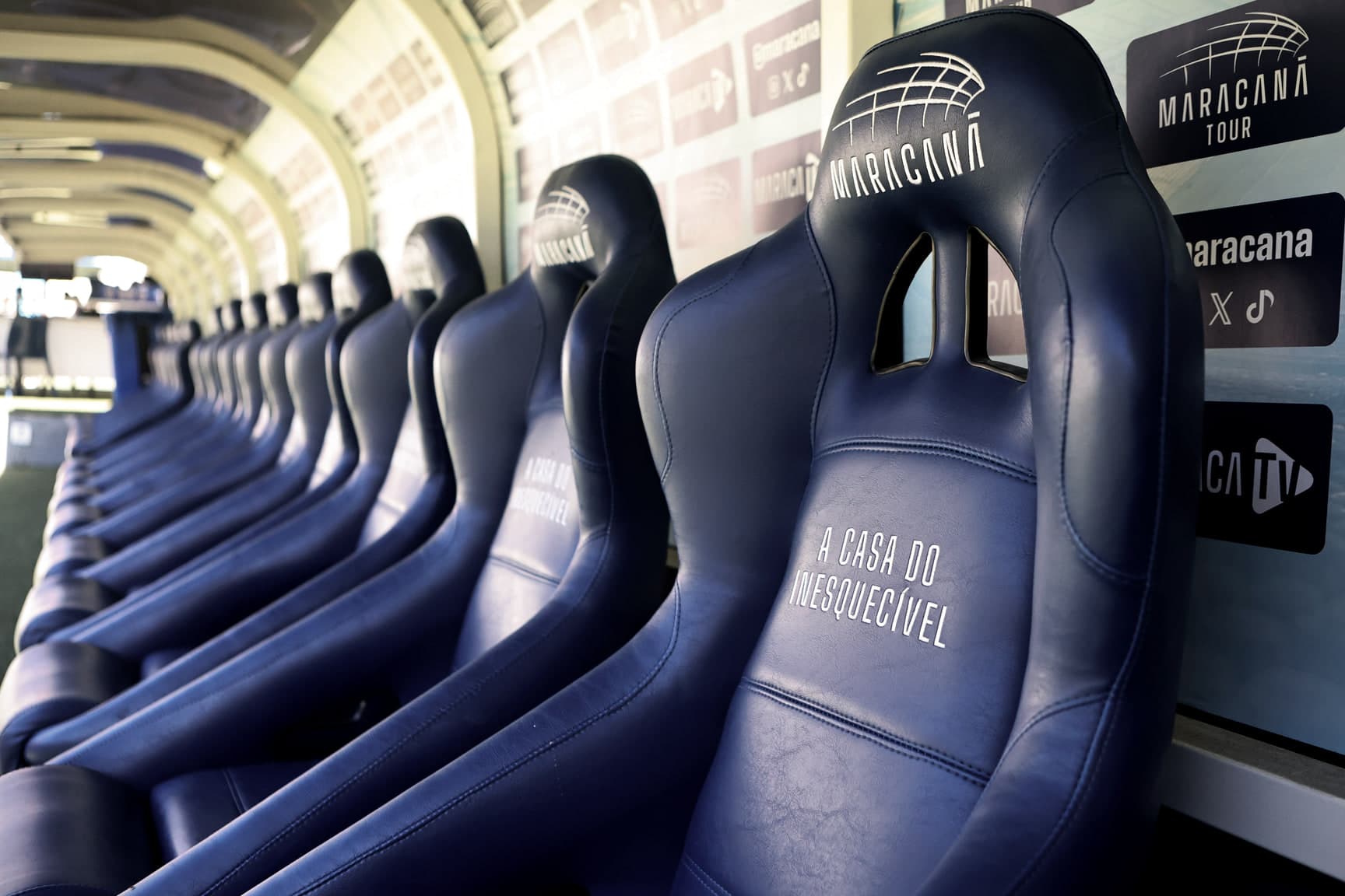 As poltronas azuis do banco de reservas do Maracanã em fileira, com o escudo do estádio e a frase "A casa do inesquecível" no encosto.